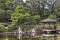 Hexagonal Gazebo Ukimido in the central pond of Mejiro Garden where carp swim and which is surrounded by large flat stones under