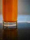 Hexagonal glass of orange juice reflected on dark induction hob