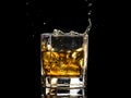 Hexagonal glass of whiskey brandy with ice and splashes from falling ice