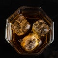 Hexagonal glass of whiskey with three cubes of real ice top view