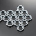 Hexagonal metal nuts arranged in a geometric pattern on a reflective gray surface. The nuts are Royalty Free Stock Photo