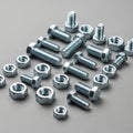 Hexagonal nuts and bolts of various sizes are arranged on a gray surface. The metal Royalty Free Stock Photo