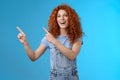 Hey check this out. Enthusiastic redhead curly stylish summer girl inviting beach party pointing upper left corner