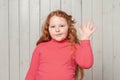 Hey how are you. Friendly redhead preteen girl waving hand, saying hello hi, welcome or greeting you