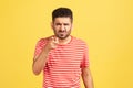 Hey you! Angry bossy man with beard in striped t-shirt grimacing pointing finger at camera, scolding and blaming you Royalty Free Stock Photo