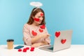 Hey you! Attractive angelic woman with kind expression sitting covered with sticker love hearts, pointing to laptop screen Royalty Free Stock Photo