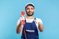 Hey you, call me. Handyman in overalls, safety gloves, holding retro phone handset and pointing to camera Royalty Free Stock Photo