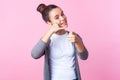 Hey you, call me! Portrait of adorable brunette teen girl smiling playfully, making telephone gesture. isolated on pink background Royalty Free Stock Photo