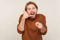 Hey you, call me! Portrait of amazed happy man holding telephone hand gesture near ear and pointing to camera Royalty Free Stock Photo