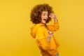 Hey you, handsome! Portrait of joyful curly-haired woman in urban style hoodie winking playfully