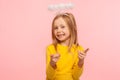 Hey you lucky! Happy cute positive little girl with angelic halo pointing fingers to camera and looking at camera Royalty Free Stock Photo