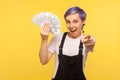 Hey you, this money can be yours! Portrait of stylish hipster girl holding dollar banknotes. yellow background, studio shot