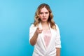 Hey you! Portrait of angry woman pointing finger at camera with serious gloomy face. blue background Royalty Free Stock Photo