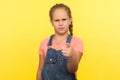 Hey you! Portrait of bossy little girl in denim overalls pointing to camera and looking with angry displeased expression Royalty Free Stock Photo