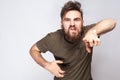 Hey You! Portrait of crazy angry bearded man with dark green t shirt against light gray background. Royalty Free Stock Photo
