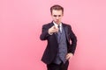 Hey you! Portrait of irritated bossy young businessman in tuxedo pointing at camera. studio shot isolated on pink background Royalty Free Stock Photo