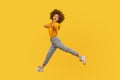 Hey you! Portrait of lively energetic curly-haired girl in urban style outfit walking through air in wide strides