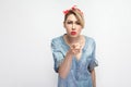 Hey you. Portrait of serious beautiful young woman in casual blue denim shirt with makeup and red headband standing and blaming or Royalty Free Stock Photo