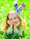 Heyday concept. Girl on smiling face spend leisure outdoors. Child enjoy spring sunny weather while lying at meadow