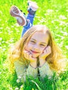 Heyday concept. Girl on smiling face spend leisure outdoors. Child enjoy spring sunny weather while lying at meadow