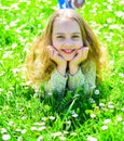Heyday concept. Girl on smiling face spend leisure outdoors. Girl lying on grass at grassplot, green background. Child