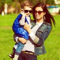 Hi & bye concept. Portrait of fashionable baby boy and his gorgeous mother in trendy sunglasses walking in the street. Mom hugging Royalty Free Stock Photo