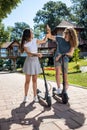 Hi five, young couple enjoying a glorious sunny day leaned on their kick scooters