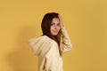 Hi handsome.Cheerful friendly caucasian woman in yellow hoodie stands sideways flirts playing with her hair.isolated over a yellow Royalty Free Stock Photo