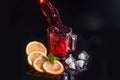 Hibiscus cold tea pouring into glass with ice, lemon and mint isolated on black background Royalty Free Stock Photo