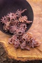 Hibiscus in sugar falls from a dark cup on a wooden background.Candied fruits