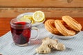 Hibiscus tea in a cup next to lemon ginger and sweets on a napkin on the table. Royalty Free Stock Photo