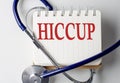 HICCUP word on notebook with medical equipment on background