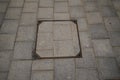 Hidden square manhole cap, grunge manhole cover. Cast iron manhole cover on the footpath old grey cobbled stone square sidewalk