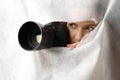Hidden woman with camera spying through hole in white fabric