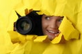 Hidden woman with camera spying through hole in paper