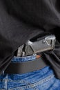 Hided handgun under the denim belt. A person is hiding a handgun under the denim belt Royalty Free Stock Photo