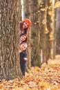 Hiding behind tree. Mother with her little son and daughter is having fun in the autumn park Royalty Free Stock Photo