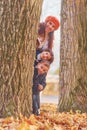 Hiding behind tree. Mother with her little son and daughter is having fun in the autumn park Royalty Free Stock Photo