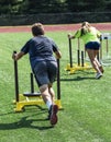 Hifh school boy and girl pushing heavy sled across field