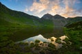 High altitude alpine lake in idyllic land once covered by glaciers. Majestic rocky mountain peak glowing at sunset. Wide angle Royalty Free Stock Photo