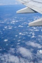 High-altitude blue sky with white clouds and partial closeup of aircraft wing Royalty Free Stock Photo