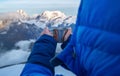 High altitude female mountaineer dressed blue warm dawn jacket holding metal mug of hot tea and drinking warm drink with