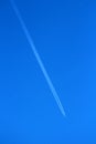 High altitude flying passenger plane over clear blue sky leaving two dense white trails Royalty Free Stock Photo