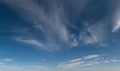 High altitude wispy clouds traveling across blue sky