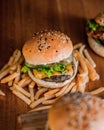 High-angel of a hamburger with sesame seeds on a toasted bun, sitting on french fries on wooden table Royalty Free Stock Photo