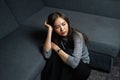 High angel view of young woman sitting sad, depression emotion on face, looking space in dark room