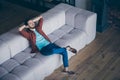 High angle above view photo of handsome guy in high spirits holding hands behind head sitting couch relaxing saturday