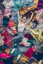 High angle above view vertical photo of cheerful funny lady spring cleaning household lying many clothes heap stack Royalty Free Stock Photo