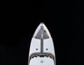 High angle aerial bird`s eye partial view of the bow of a long white luxury yacht with wooden deck in dark blue waters Royalty Free Stock Photo