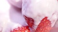 High angle appetizing ripe strawberry covered white yogurt or cream extreme close-up